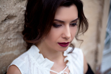 Portrait of fashion woman with glamour hairstyle. Female evening or wedding look with professional hairdo and makeup is posing outdoorl. Sexy face with wine lipstick and arrows