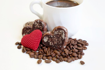 Valentine day romantic breakfast, cup of coffee, red knitted heart and gingerbreads with coffee beans on white background. Concept of love and care, morning dessert