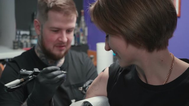 Man doing dark tattoo of snake for woman in studio