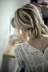 Fashion wedding hairstyle.  Hair do with an elegant hair accessorie. back view of bride look to the mirror in the morning