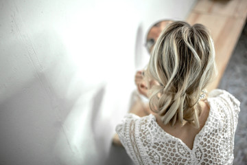 Fashion wedding hairstyle.  Hair do with an elegant hair accessorie. back view of bride look to the mirror in the morning