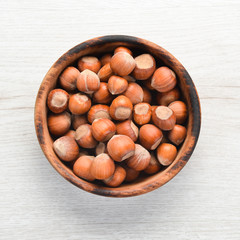 Hazelnuts in bowl on white wooden background. Nut.