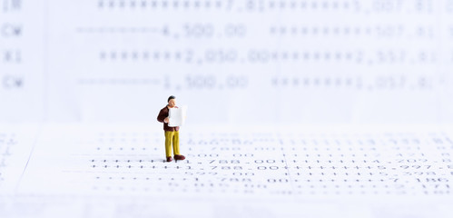 Miniature people: Businessman standing on bank passbook. retirement planning and pension. Money...