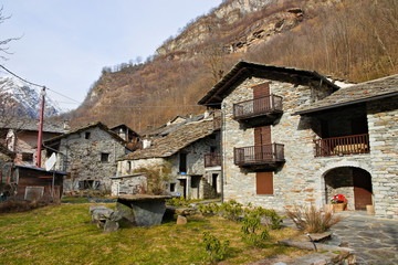 Fototapeta na wymiar Fondo, Piedmont, Italy - January 20, 2020: old abandoned rustic mountain houses made of local stone in the ancient village of Fondo, in a winter morning