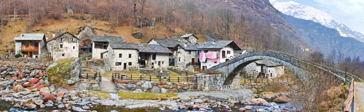 Fondo, Piedmont, Italy - January 20, 2020: Almost abandoned mountain village of Fondo, with an ancient stone bridge over the Chiusella river, on a winter day