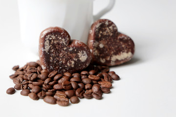 Valentines day romantic breakfast, cup of coffee and gingerbreads in heart shape with coffee beans on white background. Concept of sweet love, morning dessert