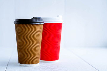 Two paper coffee cups with plastic lids. Different outside and same inside. Different color. Concept of racism. External discrimination. Coffee together. Sweet couple.