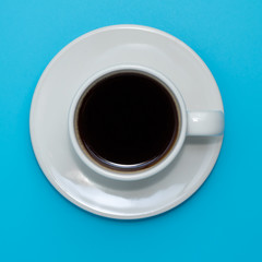 black coffee in a coffee cup top view on blue sky background.