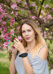 Portrait of a beautiful girl among spring foliage and flowers