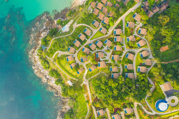 Aerial panorama of tropical resort territory and beach, beautiful Andaman sea at west coast of Phuket Island. Kata Noi beach from above, some buildings and green hills, calm sea surface to horizon