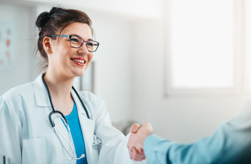 Portrait of Smiling Woman Doctor shaking the hand of a patient. Doctor and Patient Handshake
