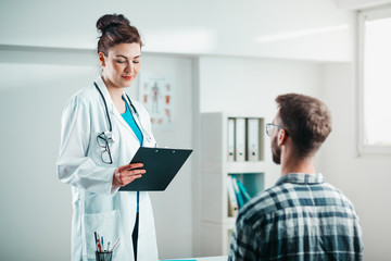 Fototapeta premium Woman Doctor reads results to Young Patient