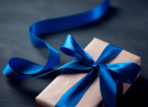 elegant gift box with blue ribbon close-up on a dark table