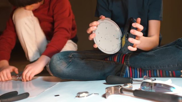 Hands of schoolchildren making a robot from electrical appliances.