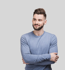Obraz premium Portrait of handsome smiling young man with folded arms. Smiling joyful cheerful men with crossed hands studio shot. Isolated on gray background