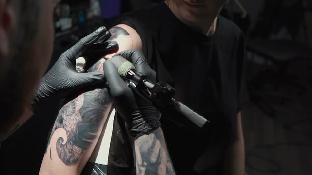 Footage of man doing tattoo of snake in studio