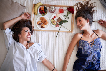 sexy homosexual couple in bed having healthy breakfast on valentines day. Love, Romance and morning concept.
