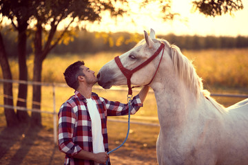 Man kissing his horse on the ranch.  Fun on countryside, sunset golden hour. Freedom nature concept.