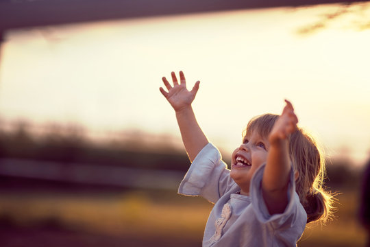 Happy kid looking at the sky . fun on countryside, sunset golden hour. Freedom nature concept.