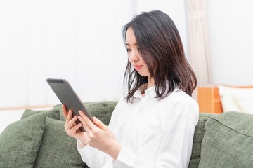 リビングでタブレットを操作する女性