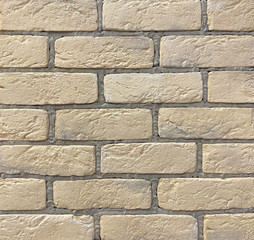 Beige brick wall with gray seams from decorative tiles for wall decoration. Background, texture