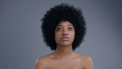 Fototapeta na wymiar Portrait of beautiful serious african girl interacting with hologram on grey background. Close-up of topless attractive afro-american girl with curly hair using a future touchscreen.