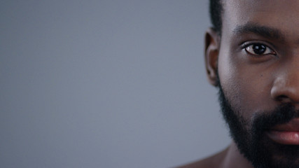 Detailed half face portrait of handsome calm african american man looking straight isolated on dark...