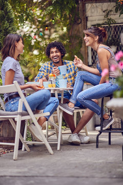 group of smiling  young friends  talking outdoor while having a coffee time.