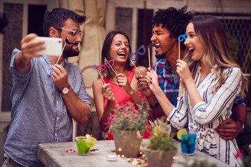 Happy group of  friends having fun with props on stick in nightclub celebrating. Party,...