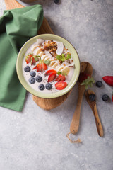 Smoothie or smoothy bowl with granola, fruits and seeds.  Organic probiotic drink or yogurt  with strawberry, on the white grey background. Gut health. Fermented dairy beverage. Trendy food. 