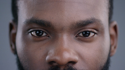 Close-up of beautiful black man eyes staring at camera. Portrait detail of serious confident african american man. - obrazy, fototapety, plakaty