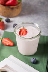 Organic probiotic milk kefir drink or yogurt in glass with strawberry, on the white grey background. Gut health. Fermented dairy beverage. Trendy food. Copy space