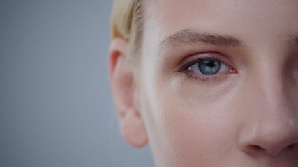 Closeup macro portrait of female face. Human woman open eyes with day beauty makeup. Girl with perfect skin and freckles.