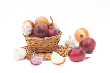 Raw rgarlic, red and purple onions in wicker basket on white background. Organic, healthy red and purple onions and garlic in wicker basket. Healthy vegetable, Allium cepa.