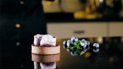 Cake with purple cream on the table near the blueberries, close-up.