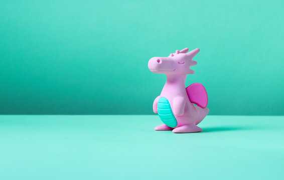 Cute rubber dragon toy on green background.