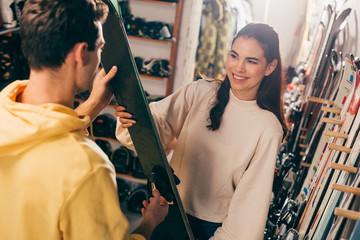 selective focus of smiling worker showing ski to client in repair shop