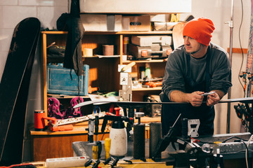 worker standing near snowboard and looking away in repair shop