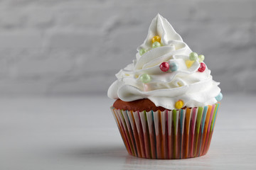 Cupcake with colorful sprinkled frosting on white background, close up