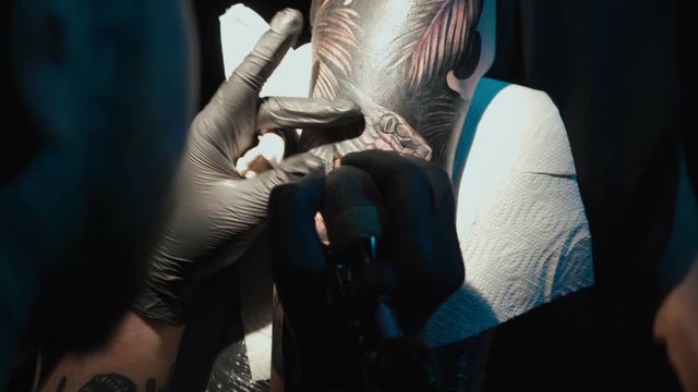 Shooting of doing dark tattoo of snake on woman in studio