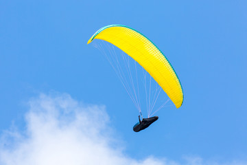 Yellow paraglider wing or canopy against blue sky with clouds