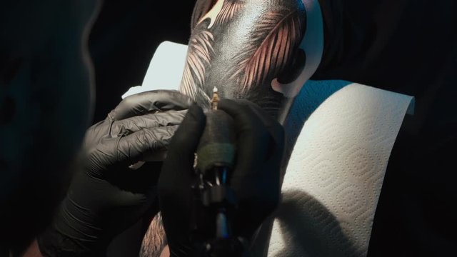 Close up video of man doing black tattoo of snake in studio
