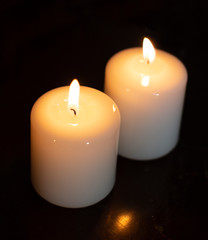 Two white candles in darkness