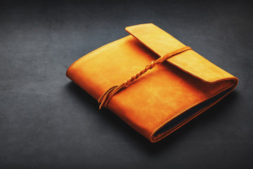 The leather cover of the album is made of brown handmade genuine leather on a black background. Elements of a leather product close-up.