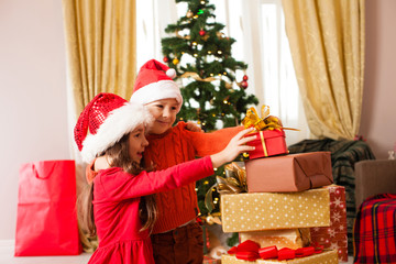 Fototapeta na wymiar Cheerful cute childrens taking christmas gifts in the room
