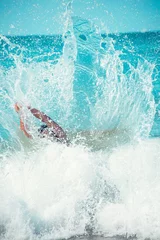Foto op Canvas Young, fit, tanned and handsome man almost submerged by the foam of the waves of a turquoise tropical sea, in the foam. Copy space above. © laura
