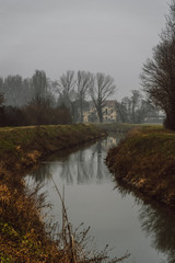 Old italian villa near a small river in a foggy winter morning