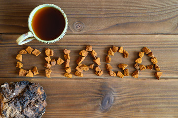 chaga tea mushroom from birch tree using for healing tea or coffee in folk medicine. the word chaga, laid out from pieces of the birch tree mushroom