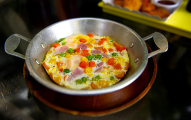 Fried eggs pan cooked from egg and corn carrots bacon ham and lantau nuts are a popular breakfast menu in Thailand Restaurant