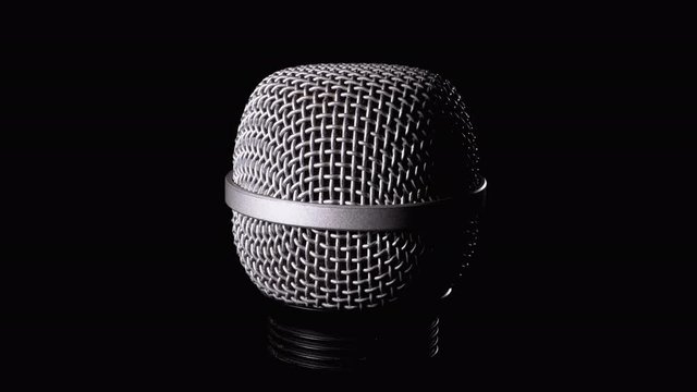 The Microphone Rotates on a Black Background. Dynamic Microphone Grid Spins Close-up